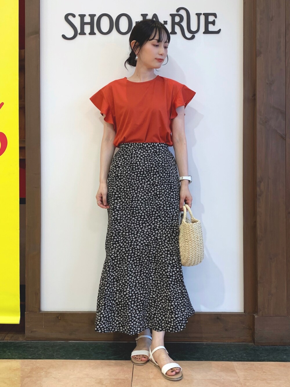 オレンジ系のTシャツ/カットソー、ブラック系のスカート、ホワイト系のショルダーバッグを着用したレディースの夏コーディネートの1枚目の写真