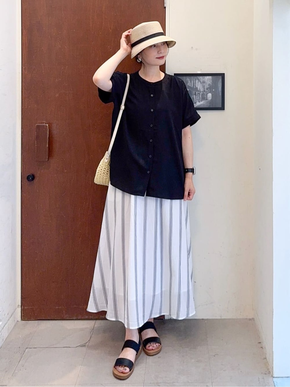 ブラック系のシャツ/ブラウス、ホワイト系のスカート、ブラック系のサンダルを着用したレディースの夏コーディネートの1枚目の写真