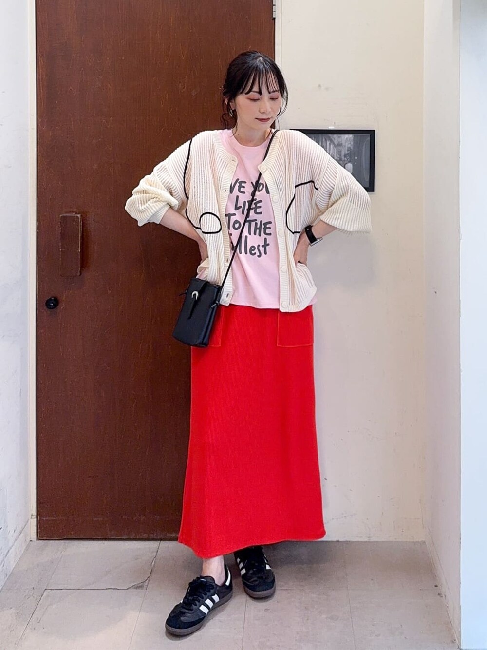 ホワイト系のカーディガン/ボレロ、ピンク系のTシャツ/カットソー、オレンジ系のスカートを着用したレディースの春コーディネートの1枚目の写真
