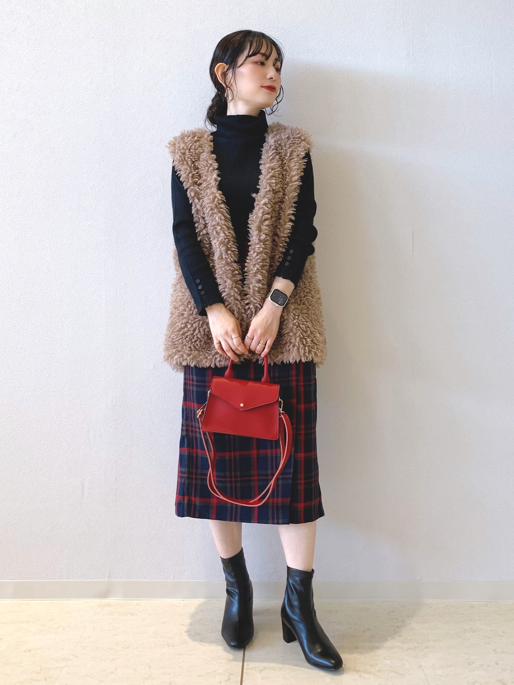 ブラック系のニット/セーター、ブラウン系のベスト、ブルー系のスカートを着用したレディースの秋コーディネートの1枚目の写真