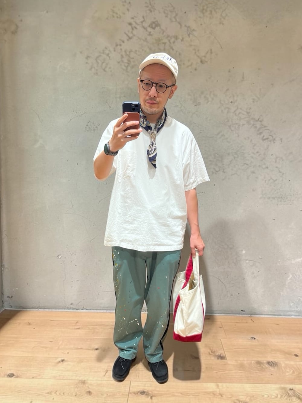 レッド系のトートバッグ、グリーン系のチノパンツ、ブラック系のモカシン/デッキシューズを着用したメンズの秋コーディネートの1枚目の写真