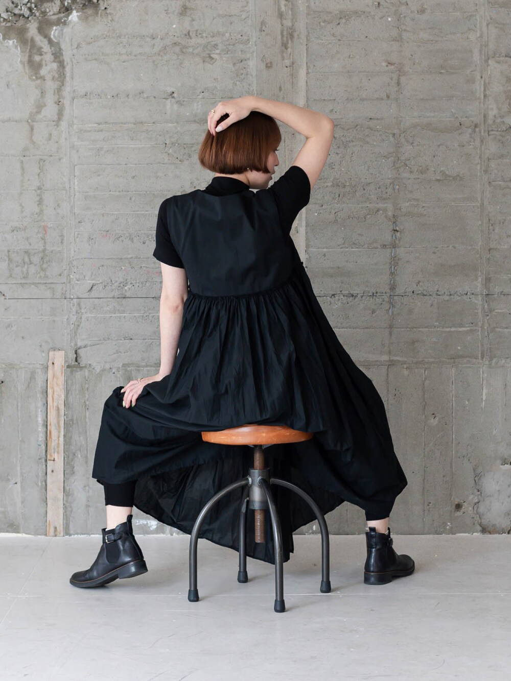 ブラック系のワンピース、ブラック系のブーツ、ブラック系のレギンス/スパッツを着用したレディースの秋コーディネートの1枚目の写真