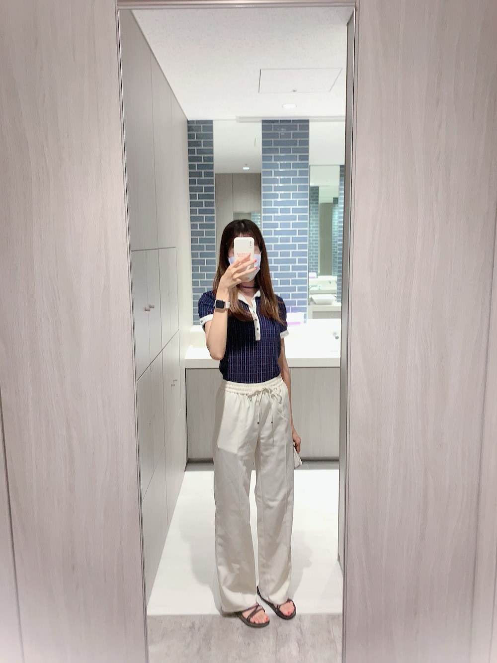 ブルー系のポロシャツ、ホワイト系のスラックスを着用したレディースの夏コーディネートの1枚目の写真