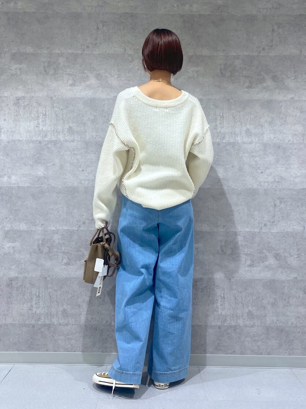 ブルー系のデニムパンツ、ホワイト系のニット/セーター、ベージュ系のトートバッグを着用したレディースの冬コーディネートの3枚目の写真