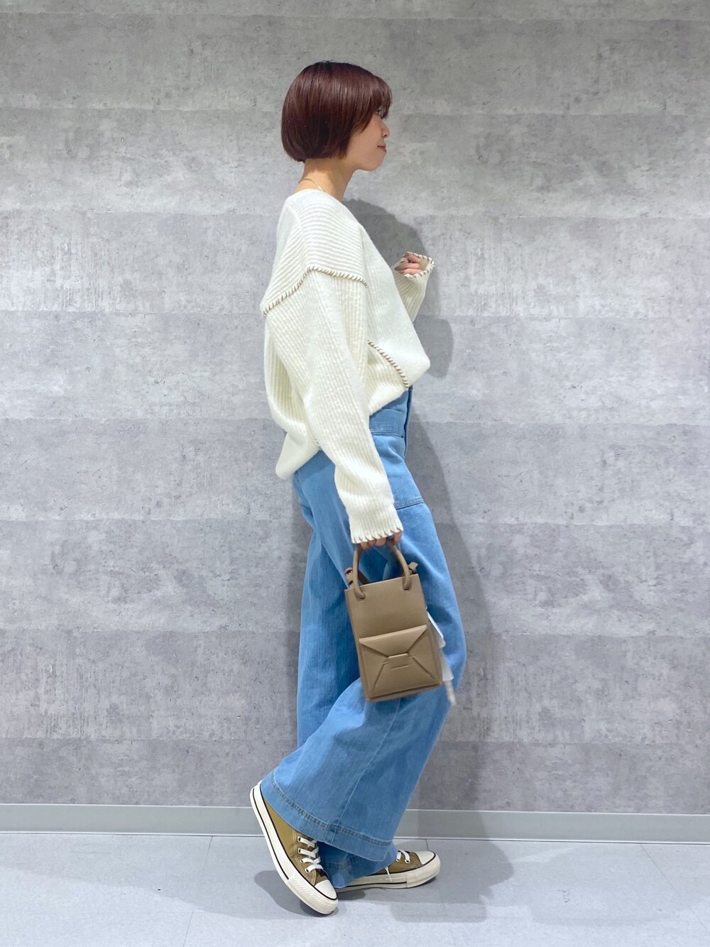 ブルー系のデニムパンツ、ホワイト系のニット/セーター、ベージュ系のトートバッグを着用したレディースの冬コーディネートの2枚目の写真