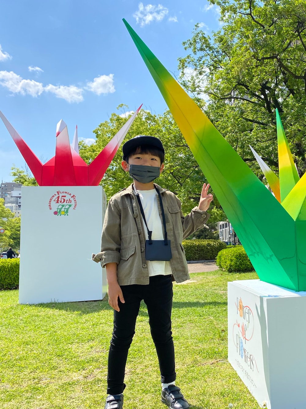 グリーン系のミリタリージャケット、ブラック系のチノパンツ、ブラック系のスニーカーを着用したキッズの春コーディネートの1枚目の写真
