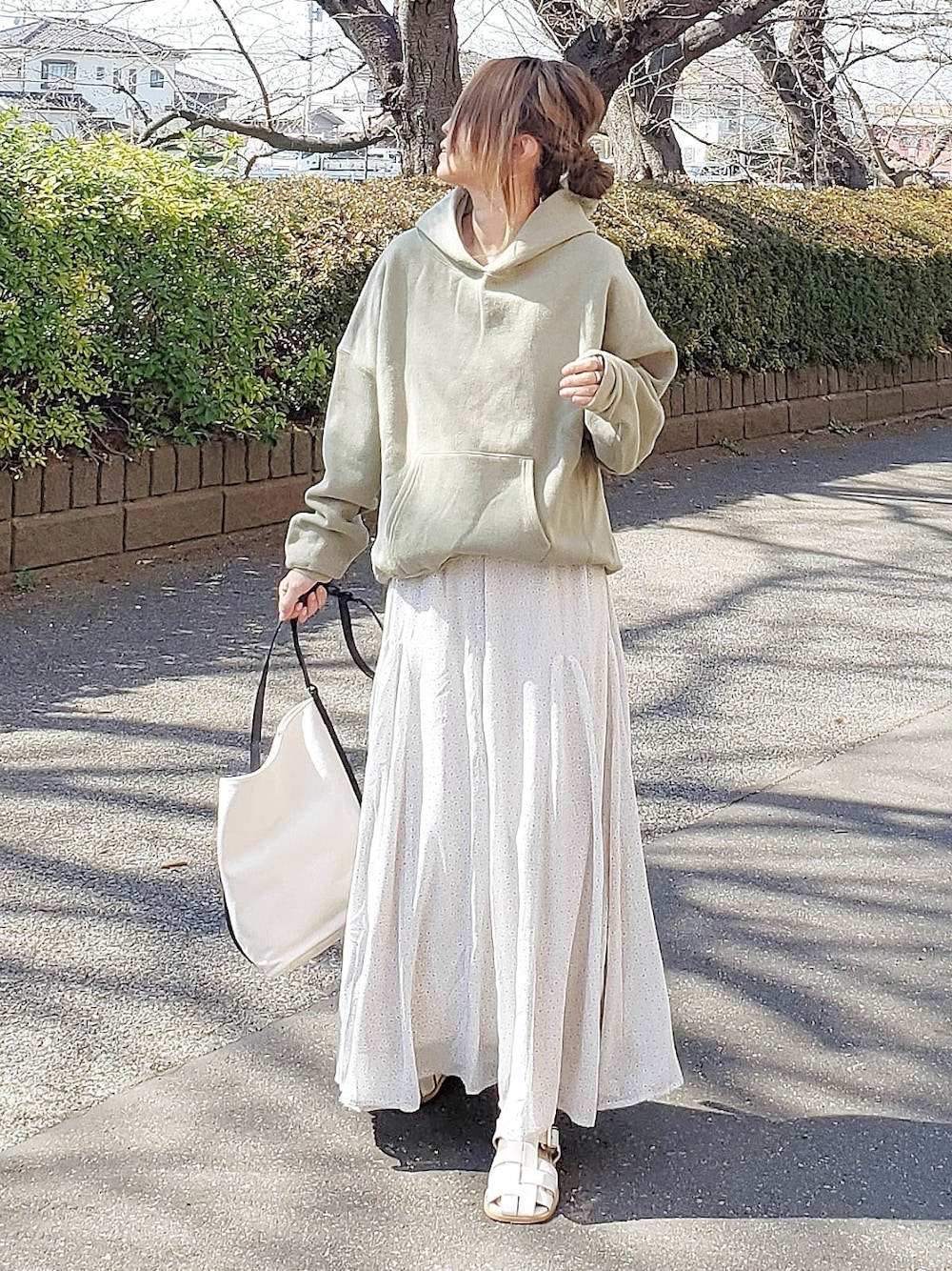 グリーン系のスカート、グリーン系のパーカー、ホワイト系のサンダルを着用したレディースの春コーディネートの2枚目の写真