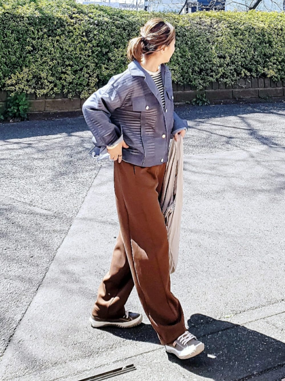 ブルー系のデニムジャケット、ブラック系のTシャツ/カットソー、ブラウン系のスウェットパンツを着用したレディースの春コーディネートの1枚目の写真