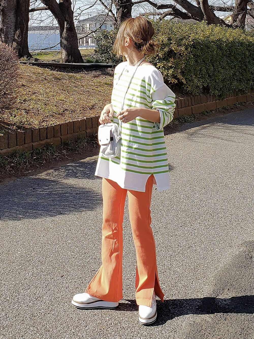 グリーン系のTシャツ/カットソー、オレンジ系のその他パンツ、ホワイト系のローファーを着用したレディースの冬コーディネートの2枚目の写真