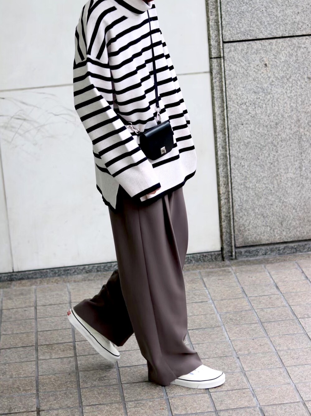 ホワイト系のニット/セーター、グレー系のスラックス、ホワイト系のスニーカーを着用したメンズの冬コーディネートの2枚目の写真