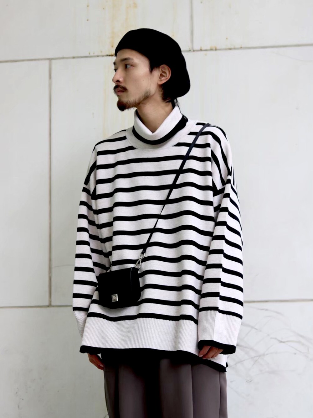 ホワイト系のニット/セーター、グレー系のスラックス、ホワイト系のスニーカーを着用したメンズの冬コーディネートの3枚目の写真