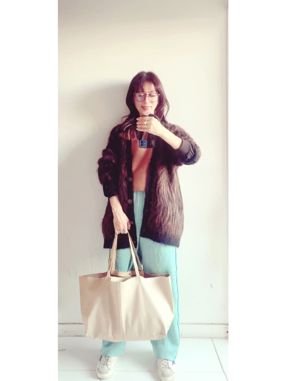 ベージュ系のトートバッグ、ホワイト系のスニーカー、ブルー系のその他パンツを着用したレディースの秋コーディネートの1枚目の写真