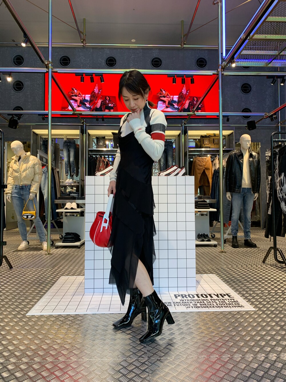 ブラック系のワンピース、ブラック系のブーツ、レッド系のハンドバッグを着用したレディースの冬コーディネートの1枚目の写真