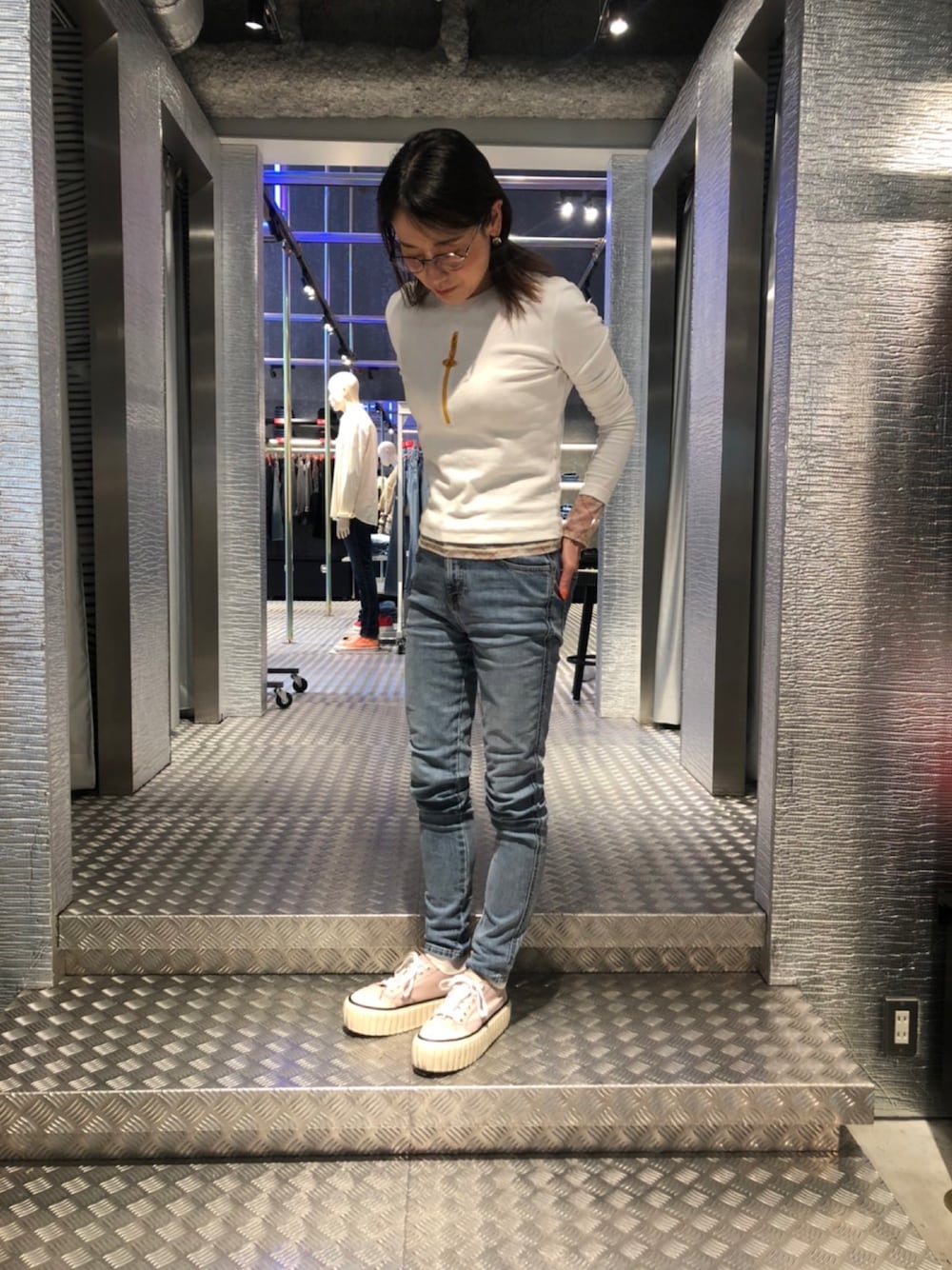 ブルー系のデニムパンツ、ピンク系のスニーカー、ホワイト系のTシャツ/カットソーを着用したレディースの春コーディネートの1枚目の写真