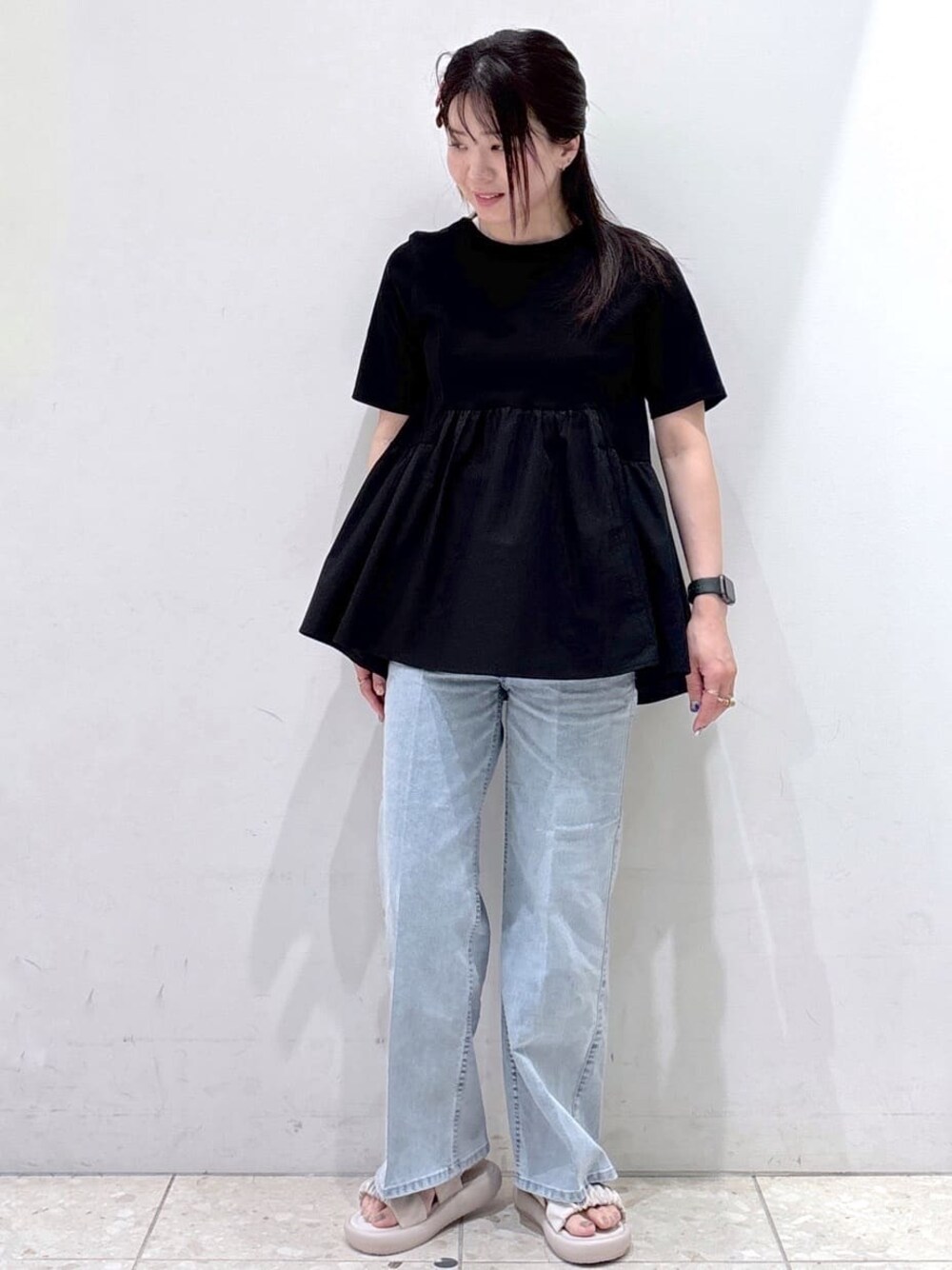 ブラック系のTシャツ/カットソー、ブルー系のデニムパンツ、ベージュ系のサンダルを着用したレディースの春コーディネートの1枚目の写真