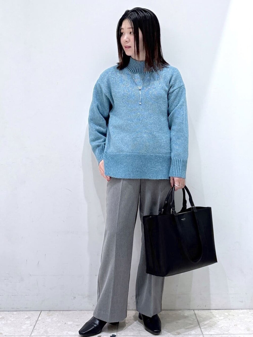 ブルー系のニット/セーター、グレー系のその他パンツ、ブラック系のトートバッグを着用したレディースの冬コーディネートの1枚目の写真