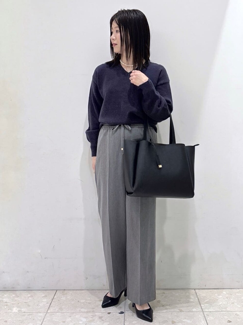 ブルー系のニット/セーター、グレー系のその他パンツ、ブラック系のトートバッグを着用したレディースの冬コーディネートの1枚目の写真