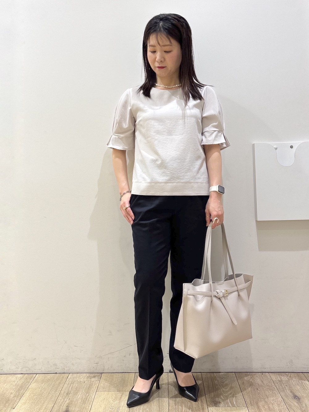 ブラック系のパンプス、グレー系のトートバッグ、ブルー系のその他パンツを着用したレディースの春コーディネートの1枚目の写真