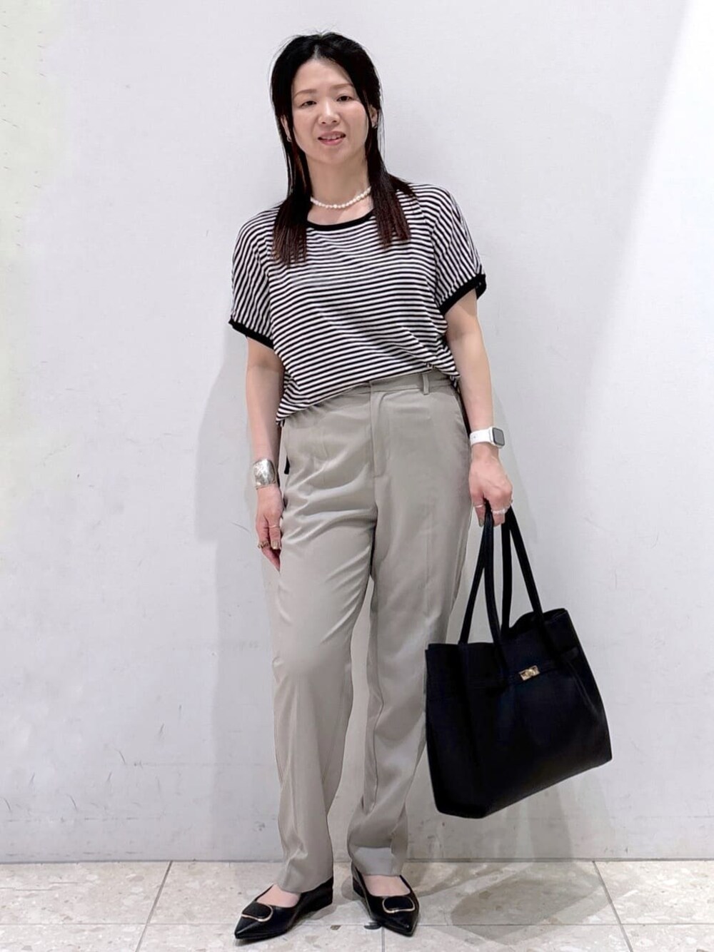 ブラック系のニット/セーター、ブラウン系のその他パンツ、ブラック系のトートバッグを着用したレディースの夏コーディネートの1枚目の写真