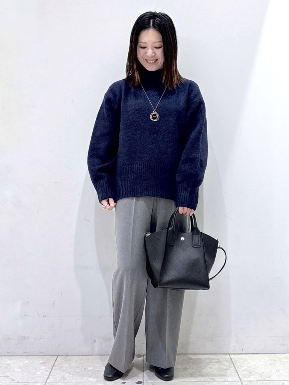 ブルー系のニット/セーター、グレー系のその他パンツ、ブラック系のショルダーバッグを着用したレディースの冬コーディネートの1枚目の写真