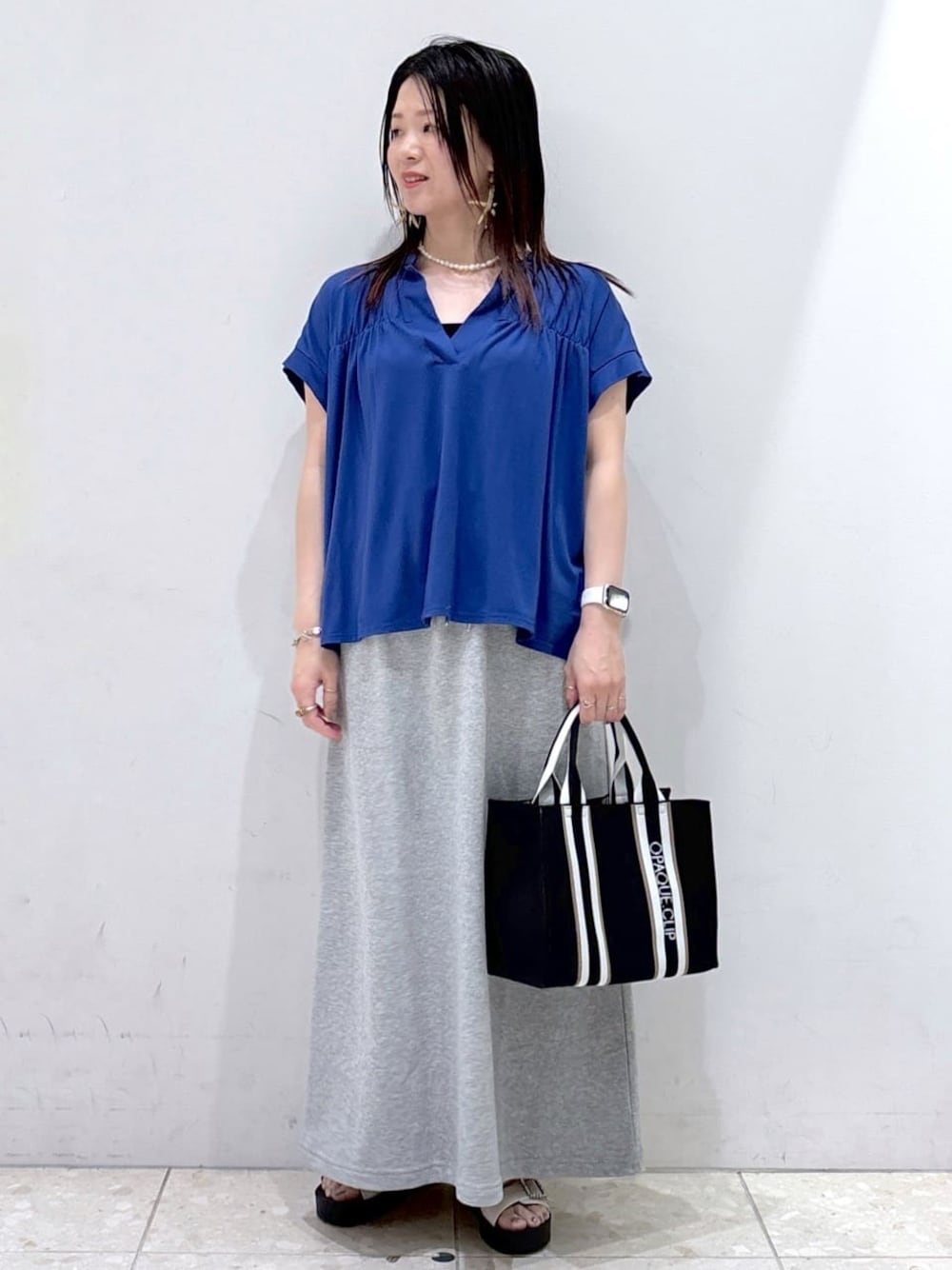 ブルー系のTシャツ/カットソー、グレー系のスカート、ブラック系のトートバッグを着用したレディースの夏コーディネートの1枚目の写真