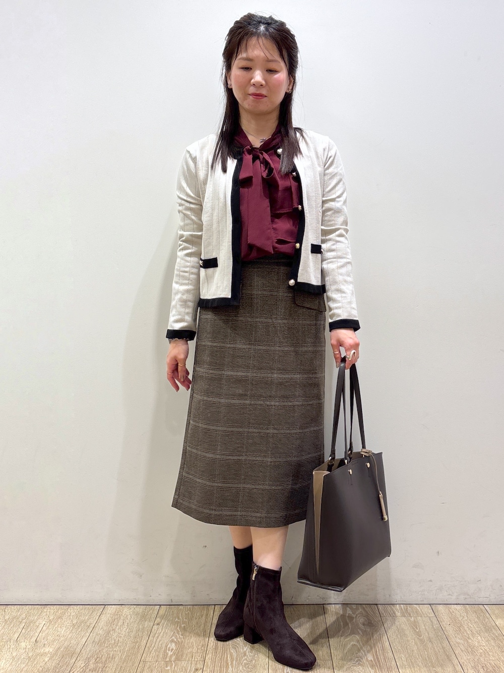 ベージュ系のカーディガン/ボレロ、レッド系のシャツ/ブラウス、ブラウン系のスカートを着用したレディースの秋コーディネートの1枚目の写真