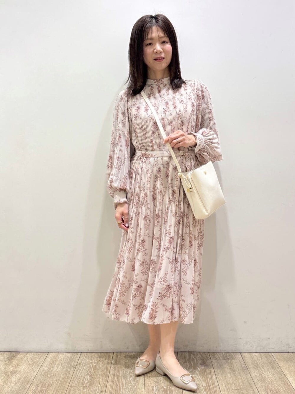 ホワイト系のショルダーバッグ、ベージュ系のパンプス、レッド系のスカートを着用したレディースの冬コーディネートの1枚目の写真