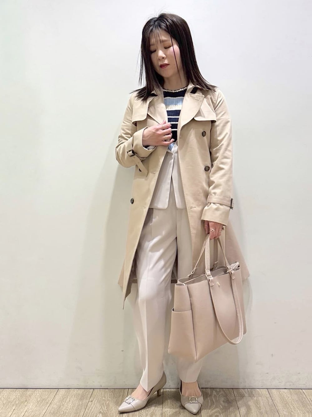 ベージュ系のトレンチコート、ベージュ系のノーカラージャケット、ブルー系のニット/セーターを着用したレディースの春コーディネートの1枚目の写真