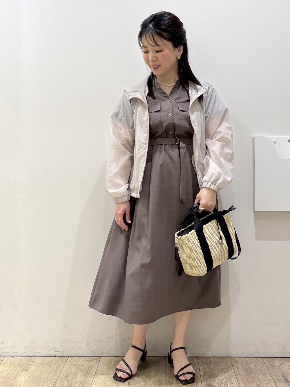 ベージュ系のブルゾン、ブラウン系のワンピース、ブラック系のトートバッグを着用したレディースの春コーディネートの1枚目の写真