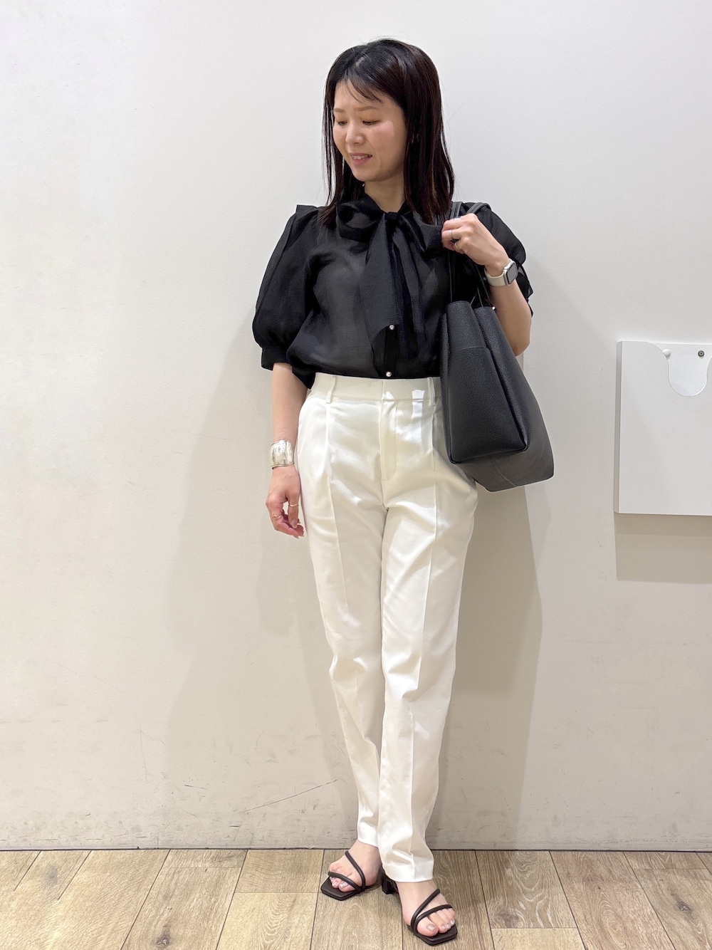 ブラック系のトートバッグ、ブラウン系のサンダル、ホワイト系のその他パンツを着用したレディースの春コーディネートの1枚目の写真