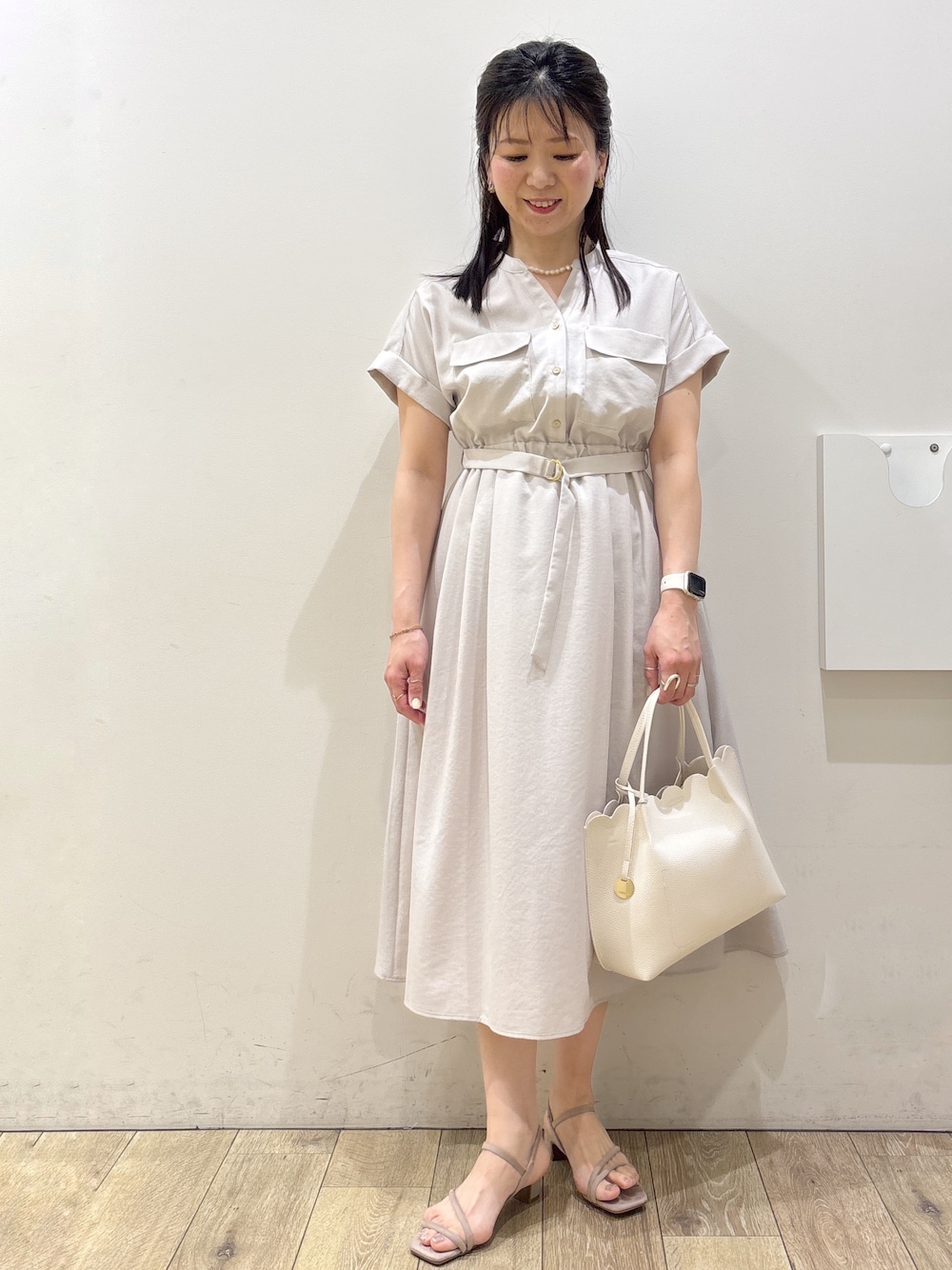 ベージュ系のワンピース、ホワイト系のトートバッグ、ベージュ系のサンダルを着用したレディースの春コーディネートの1枚目の写真