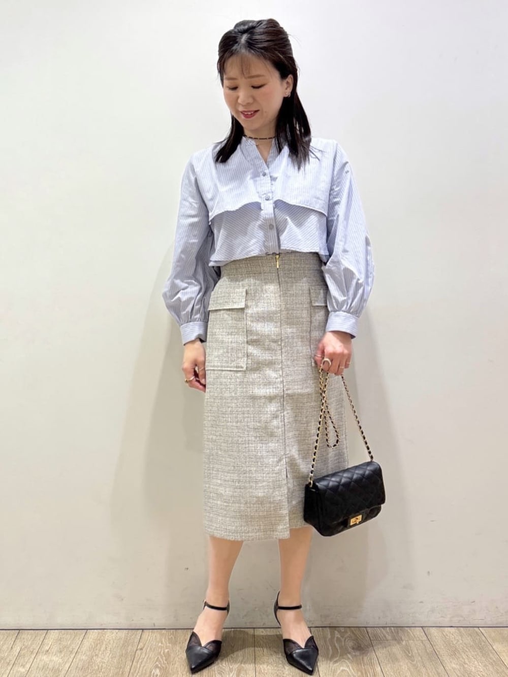 ブラック系のパンプス、ベージュ系のスカート、ブルー系のシャツ/ブラウスを着用したレディースの春コーディネートの1枚目の写真