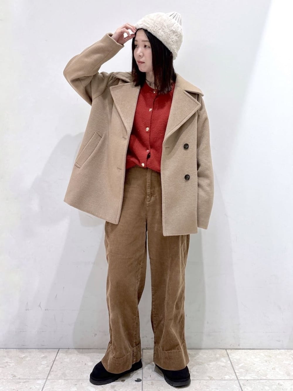 ベージュ系のピーコート、レッド系のカーディガン/ボレロ、イエロー系のその他パンツを着用したレディースの冬コーディネートの1枚目の写真