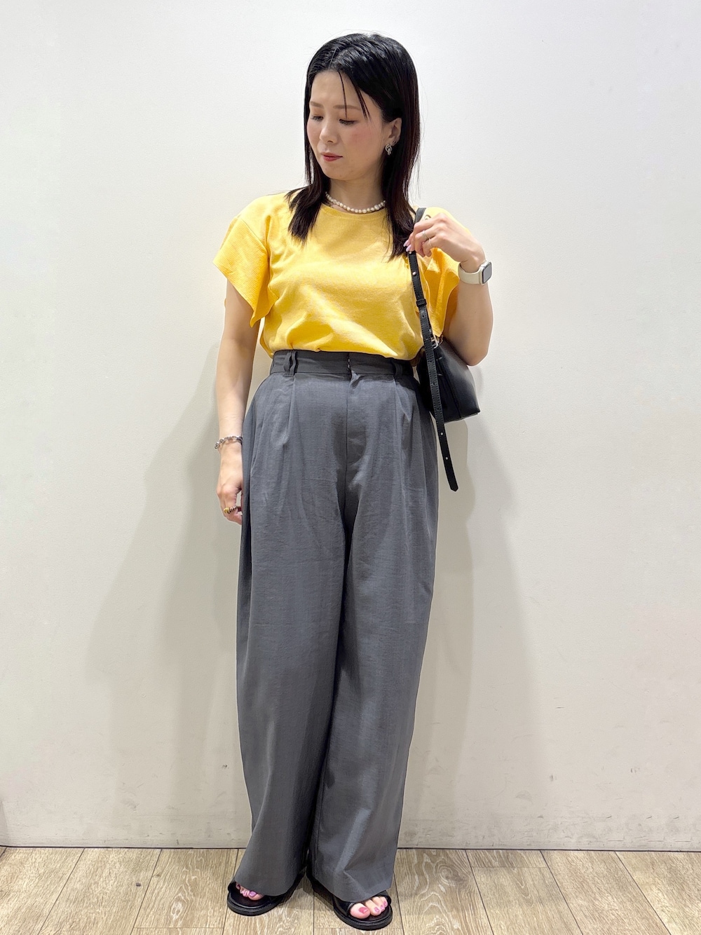 イエロー系のニット/セーター、グレー系のその他パンツ、ブラック系のショルダーバッグを着用したレディースの夏コーディネートの1枚目の写真