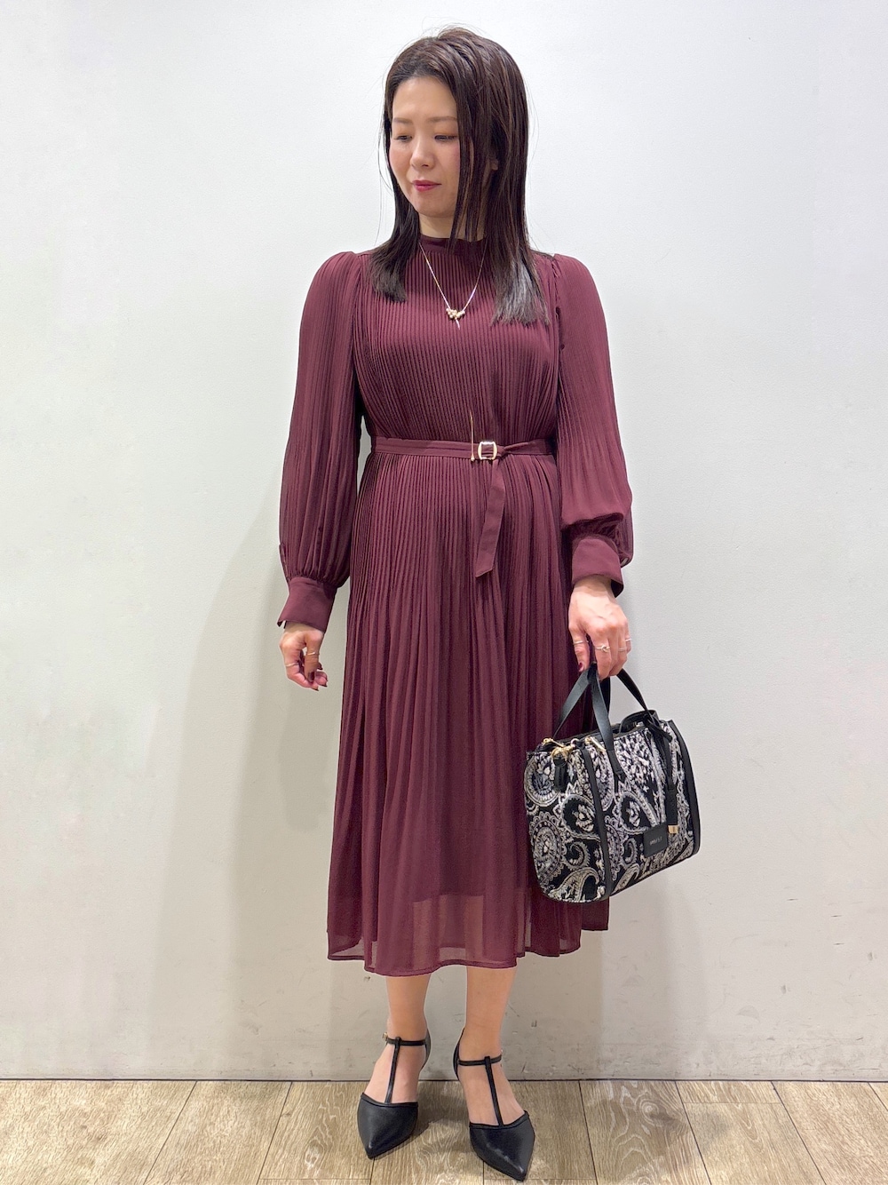 レッド系のワンピース、ブラック系のトートバッグ、ブラック系のパンプスを着用したレディースの秋コーディネートの1枚目の写真