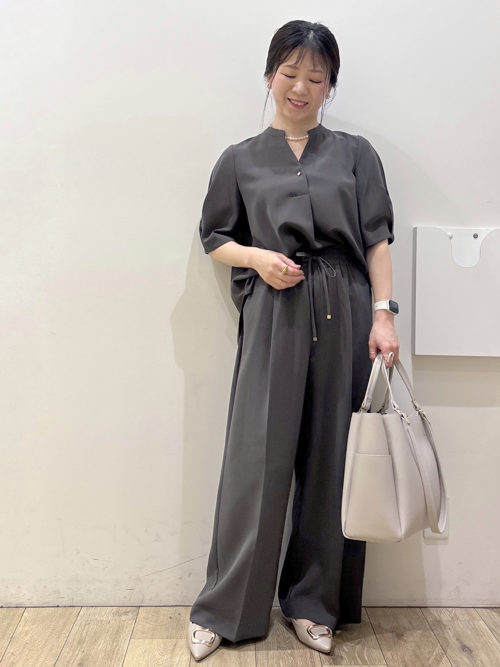ベージュ系のパンプス、グレー系のカーディガン/ボレロ、ベージュ系のトートバッグを着用したレディースの春コーディネートの1枚目の写真