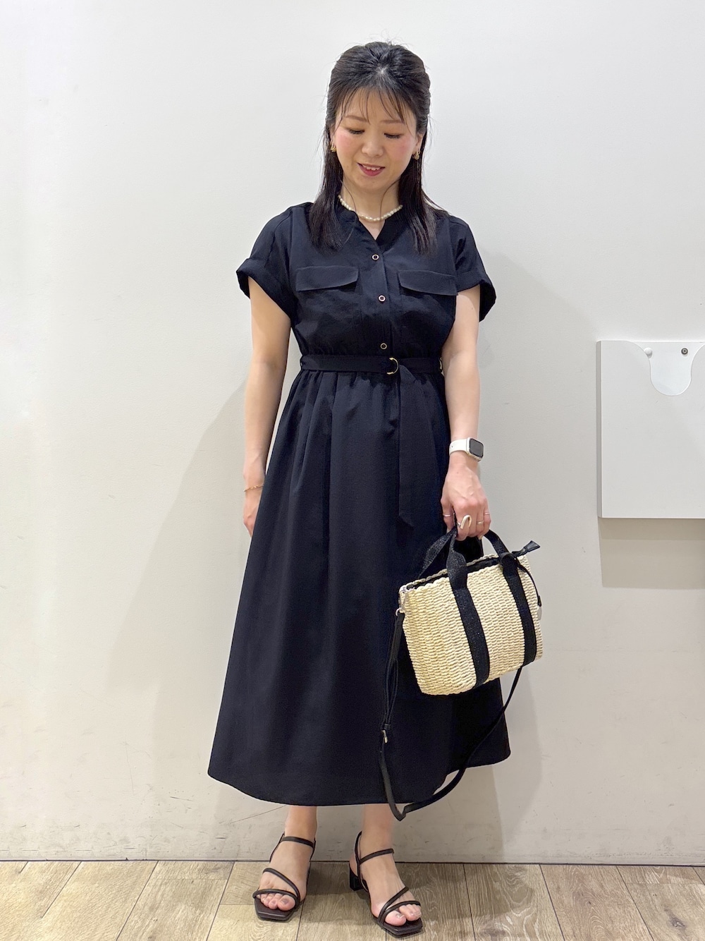 ブルー系のワンピース、ブラック系のトートバッグ、ブラウン系のサンダルを着用したレディースの春コーディネートの1枚目の写真