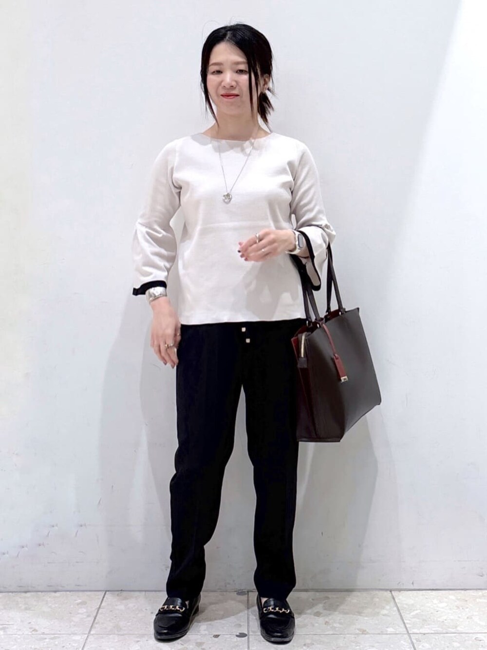 グレー系のニット/セーター、ブラック系のその他パンツ、ブラウン系のトートバッグを着用したレディースの秋コーディネートの1枚目の写真