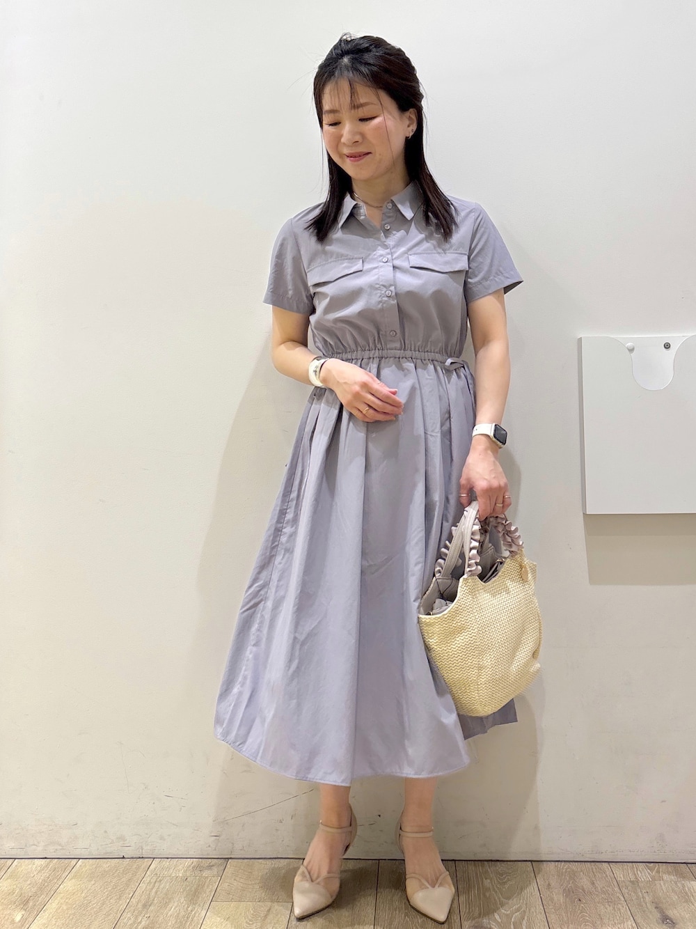 グレー系のワンピース、ベージュ系のトートバッグ、ベージュ系のパンプスを着用したレディースの春コーディネートの1枚目の写真