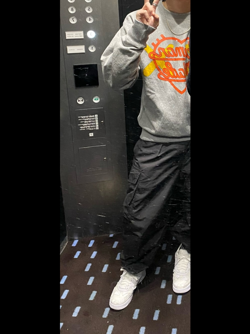 グレー系のスウェット、ブラック系のカーゴパンツ、ホワイト系のスニーカーを着用したメンズの冬コーディネートの1枚目の写真