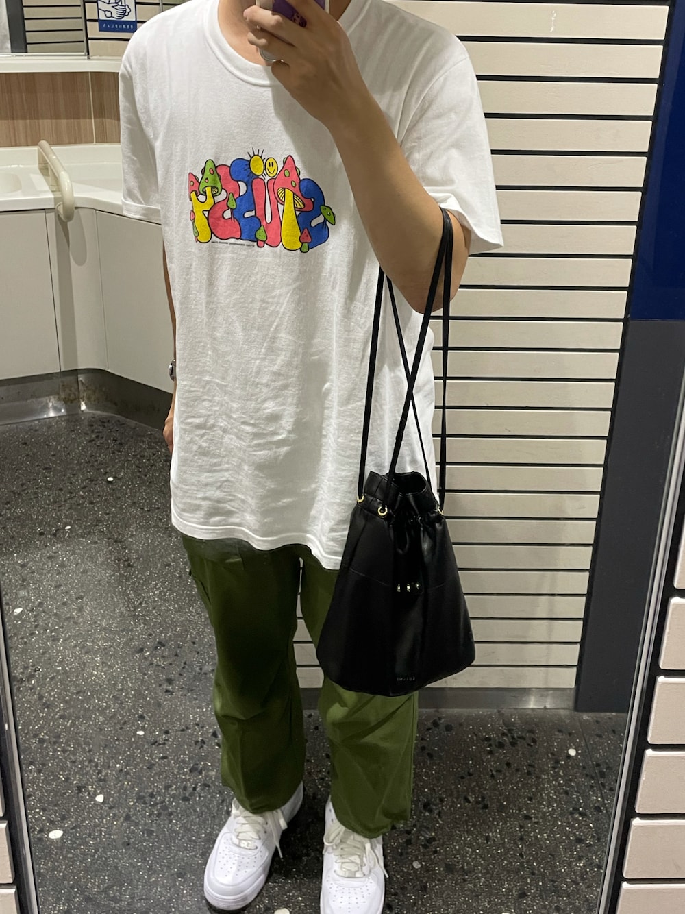 グリーン系のカーゴパンツ、ホワイト系のスニーカー、ブラック系のショルダーバッグを着用したメンズの秋コーディネートの1枚目の写真