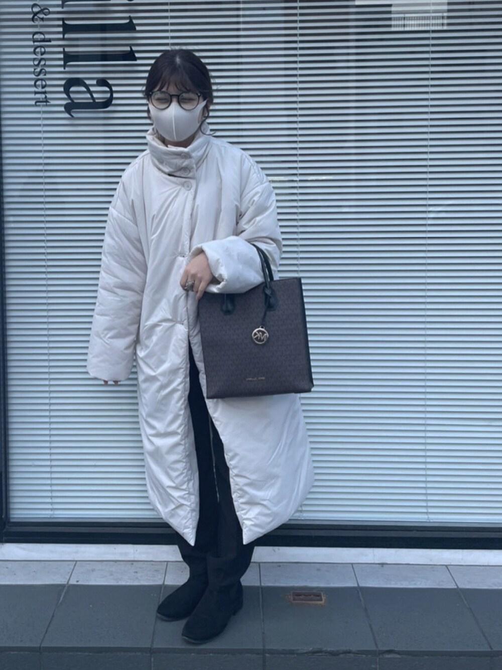 ホワイト系のダウンジャケット/コート、ブラウン系のトートバッグ、ブラック系のブーツを着用したレディースの冬コーディネートの1枚目の写真