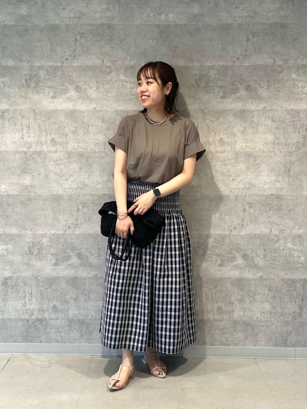 ブラック系のトートバッグ、パープル系のスカート、グリーン系のTシャツ/カットソーを着用したレディースの春コーディネートの1枚目の写真