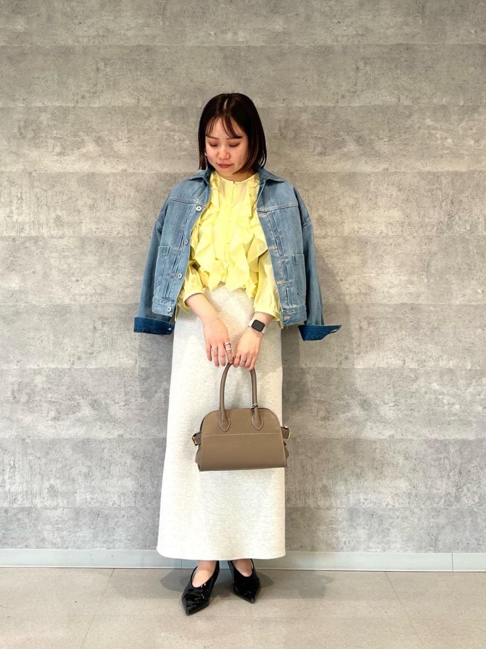 ベージュ系のスカート、イエロー系のシャツ/ブラウス、ブルー系のデニムジャケットを着用したレディースの冬コーディネートの1枚目の写真