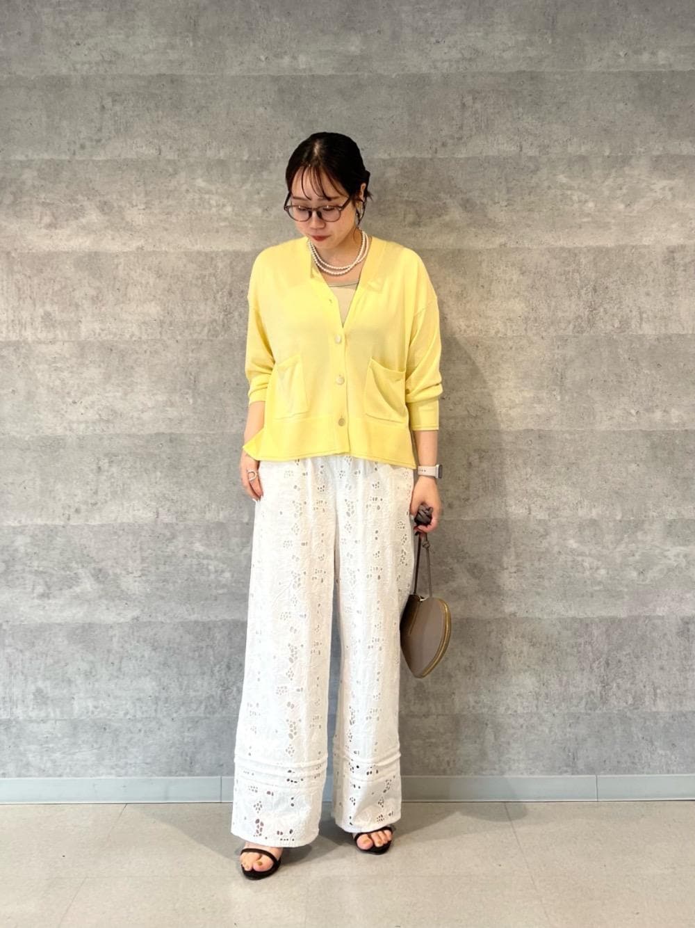 グリーン系のタンクトップ、イエロー系のカーディガン/ボレロ、ホワイト系のその他パンツを着用したレディースの春コーディネートの1枚目の写真