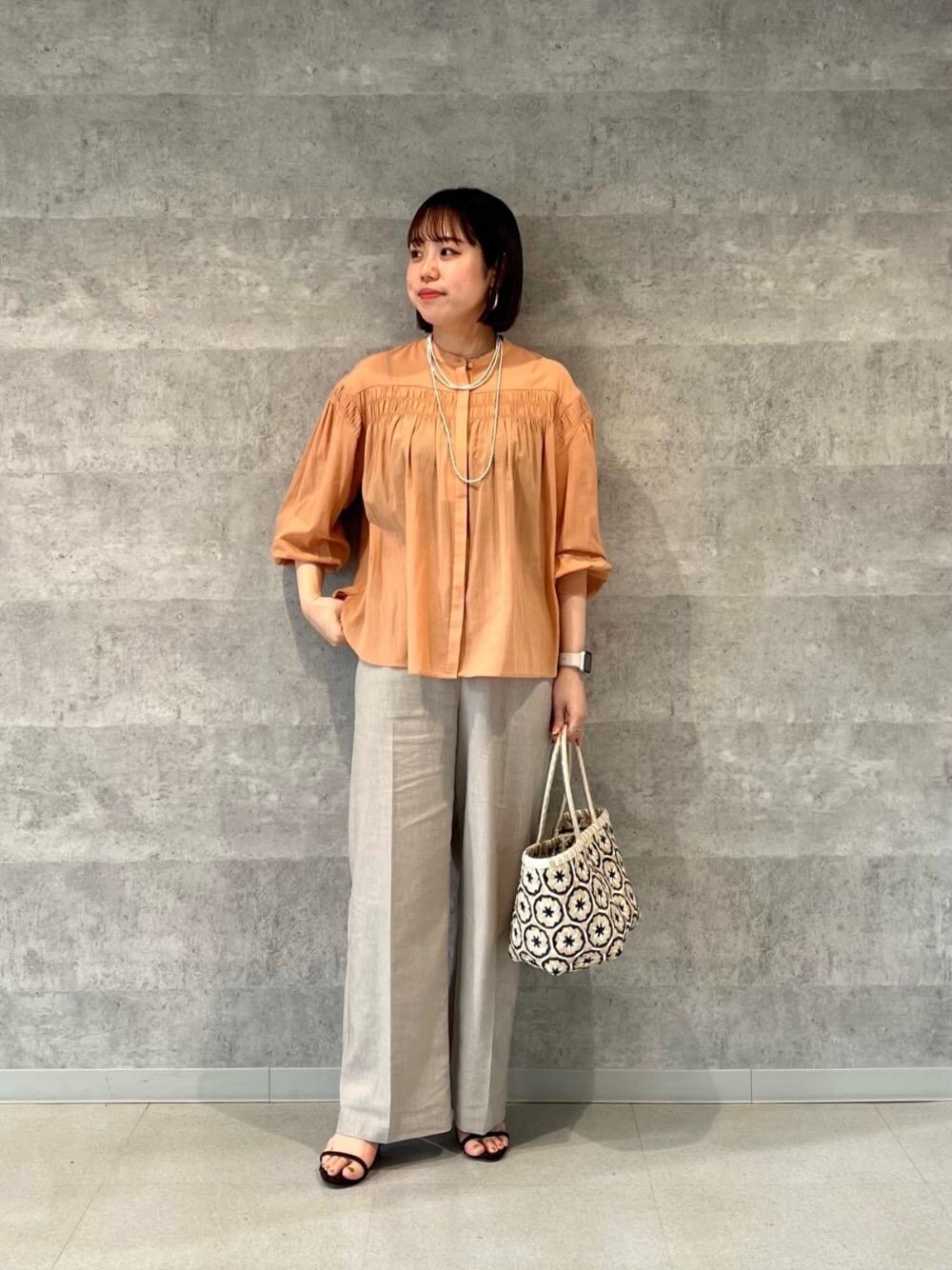 オレンジ系のシャツ/ブラウス、ベージュ系のその他パンツ、ベージュ系のトートバッグを着用したレディースの春コーディネートの1枚目の写真