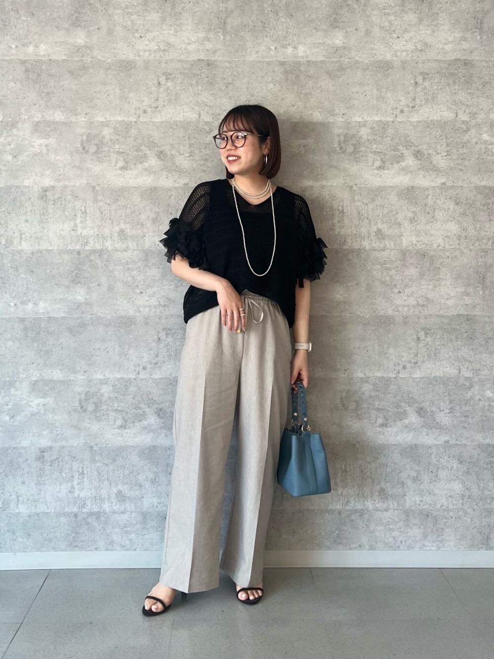 ベージュ系のその他パンツ、ブルー系のショルダーバッグ、ブラック系のニット/セーターを着用したレディースの春コーディネートの1枚目の写真