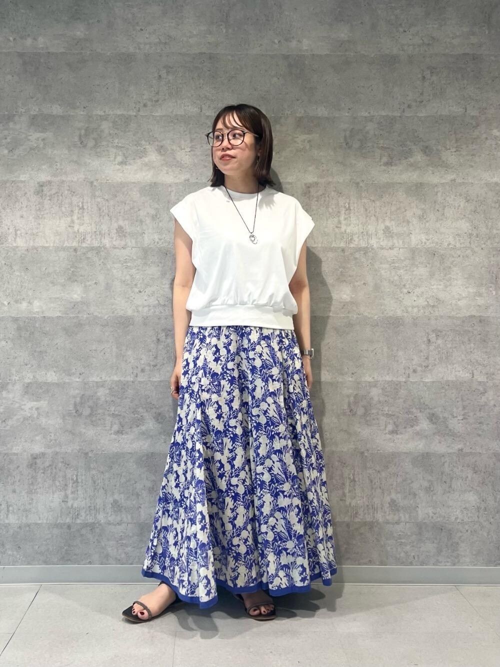 ブルー系のスカート、ホワイト系のTシャツ/カットソー、シルバー系のネックレスを着用したレディースの春コーディネートの1枚目の写真