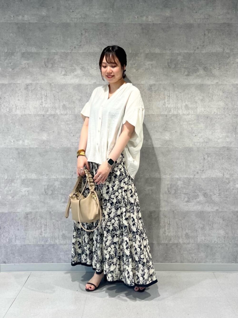 ベージュ系のショルダーバッグ、ブラック系のスカート、ホワイト系のシャツ/ブラウスを着用したレディースの春コーディネートの1枚目の写真