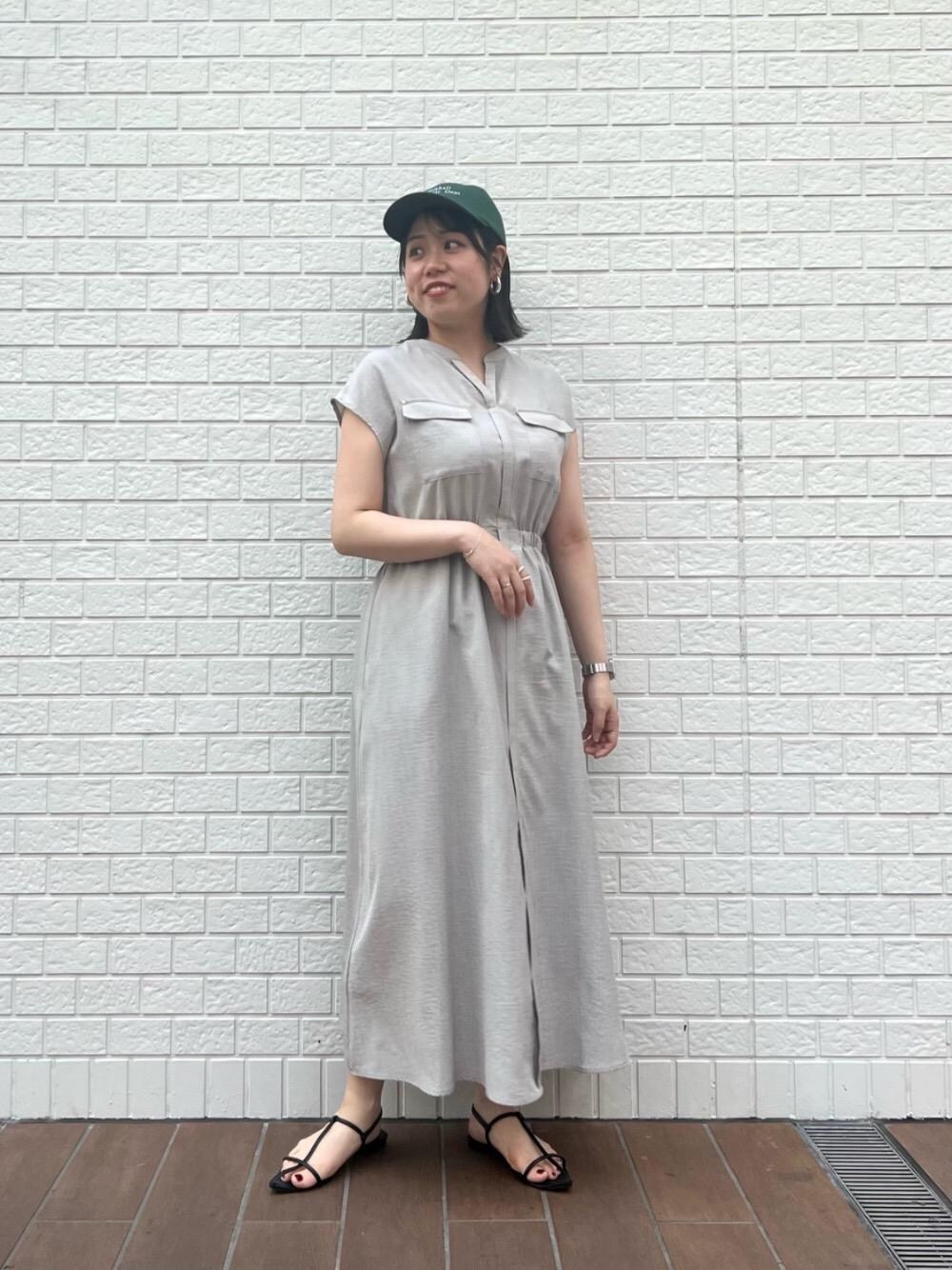 ベージュ系のワンピース、グリーン系のキャップを着用したレディースの夏コーディネートの1枚目の写真